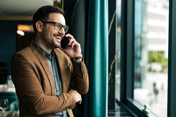 Image shows a man smiling and talking on the phone for a phone interview. All StarZ Staffing.