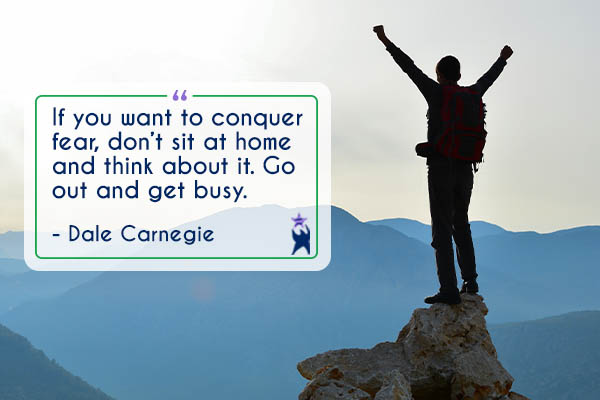 Image shows a climber at the top of a mountain peak with their hands raised celebrating success. Text is a quote reading: "If you bwant to conquer fear, don't sit at home and think about it. Go out and get busy" - Dale Carnegie. All StarZ Staffing.