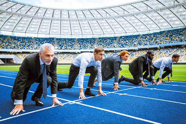 Talent Shortages in the Puget Sound: Image shows a diverse group of business professionals crouching at the starting line of a race track. All StarZ Staffing.