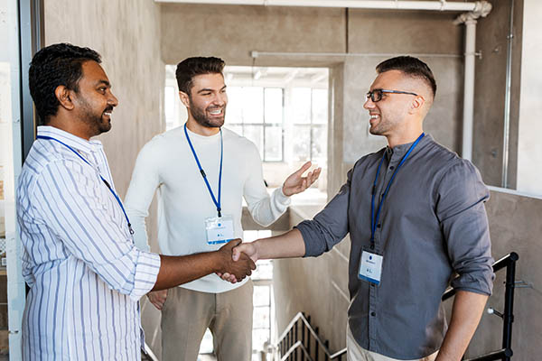 Talent Shortages in the Puget Sound: Image shows a male worker introducing a new employee to another team member. The new employee is shaking hands with the team member. All StarZ Staffing.