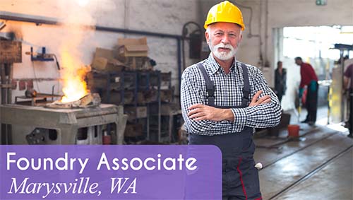 Male worker smiles and stands with arms crossed with foundry in the background. White text over a purple banner reads: 'Foundry Associate in Marysville, WA.