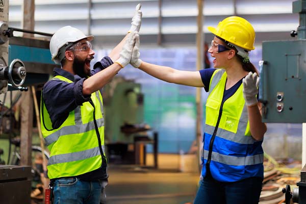 Two manufacturing workers celebrate successfully solving a problem