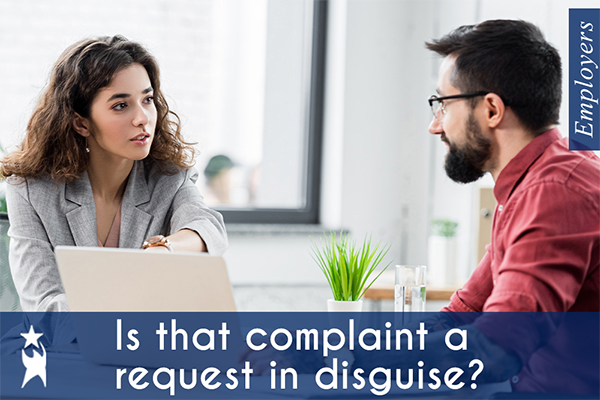 Two professionals sit at a table discussing something on a laptop. One gestures toward the screen as they engage in conversation. Overlay text says, "Is that complaint a request in disguise?" emphasizing the idea that complaints often reveal underlying needs or requests.